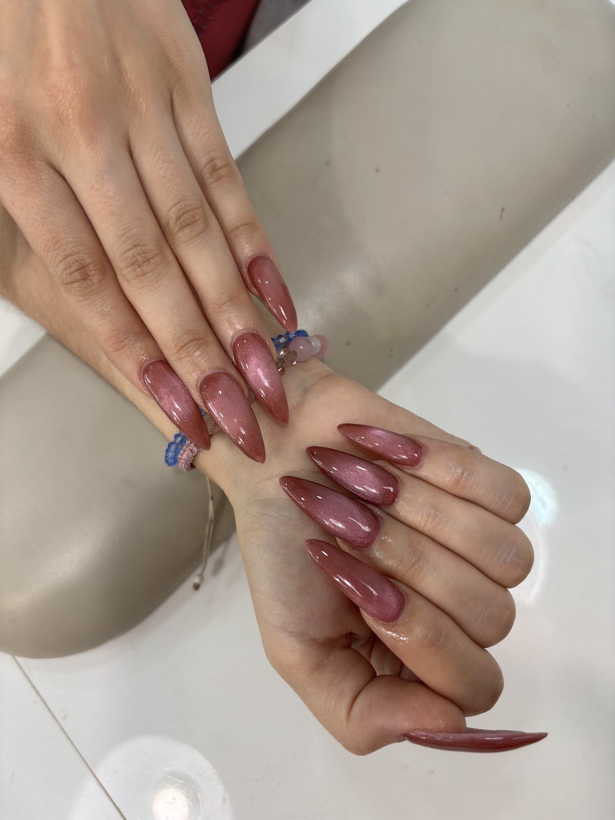 Ongles longs en amande, vernis semi-permanent brun rosé brillant.