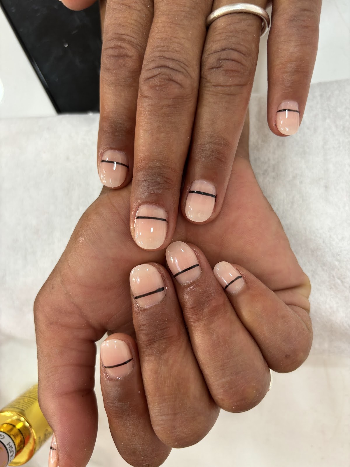 Ongles nude en amande, traversés d'une fine ligne noire, style minimaliste.
