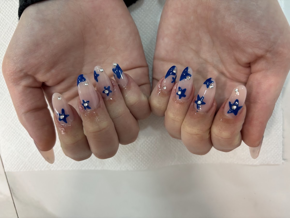 Ongles longs translucides à motifs d'étoiles bleues.